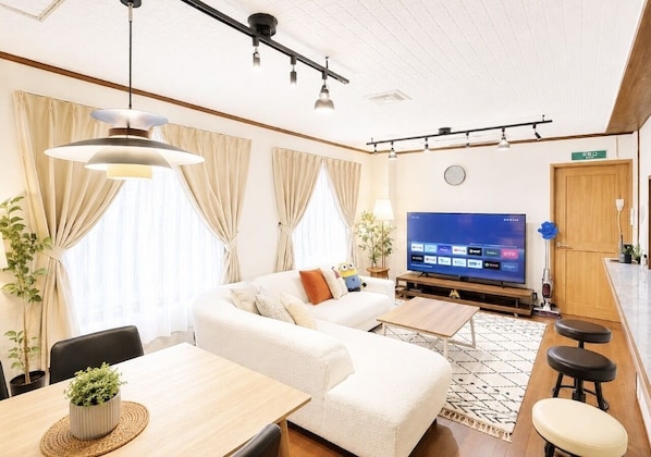 En moderne stue med sofa, spisebord, fjernsyn og barområde.