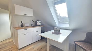 Una cucina moderna con un piano di lavoro bianco, una macchina per il caffè e una bottiglia di vino.