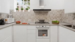 A modern kitchen with white cabinets, a gas stove, a microwave, and a window with plants.
