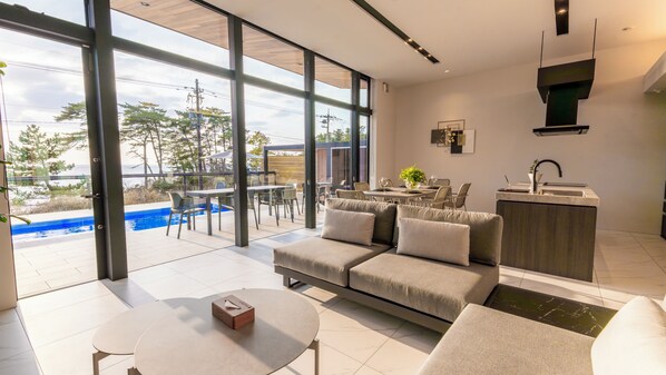 A modern living room with a sofa, coffee table, and dining area. - Morris Resort Tohginbow (Sakai)