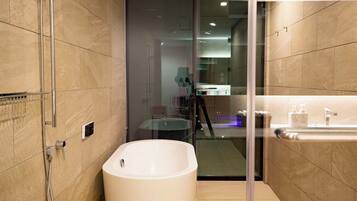A modern bathroom with a freestanding bathtub, a glass shower enclosure, and a visible bathroom counter with a sink and mirror.