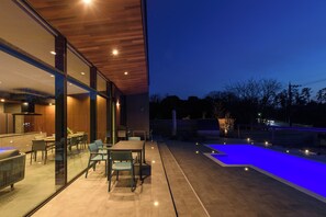 A modern outdoor patio with a swimming pool, glass walls, and a wooden ceiling. - Morris Resort Tohginbow (Sakai)