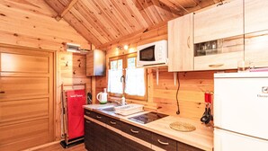 A compact kitchen with wooden cabinets, a microwave, a sink, and a refrigerator.