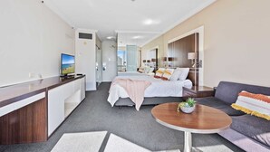 A modern hotel room with a bed, a sofa, a desk, and a TV. - Ocean View Surfers Paradise Studio Suite (Surfers Paradise)