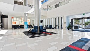 A spacious lobby with a high ceiling, a reception desk, and seating area with blue chairs. - Ocean View Surfers Paradise Studio Suite (Surfers Paradise)