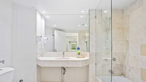 A modern bathroom with a glass-enclosed shower, a sink with a mirror, and a toilet. - Ocean View Surfers Paradise Studio Suite (Surfers Paradise)