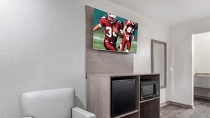 Ein modernes Wohnzimmer mit einem Flachbildfernseher, einer bequemen Couch und einem Wandbild mit Fußballspielern.