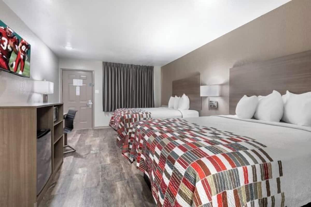 Una habitación de hotel con una cama grande, un escritorio, una silla y un televisor en la pared.