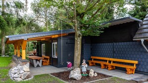 A small outdoor seating area with benches and a table, surrounded by a stone wall and a tree. - Haus Schönblick - Apartment 5 with Mountain View, Private Terrace and Wi-Fi (Willingen (Upland))