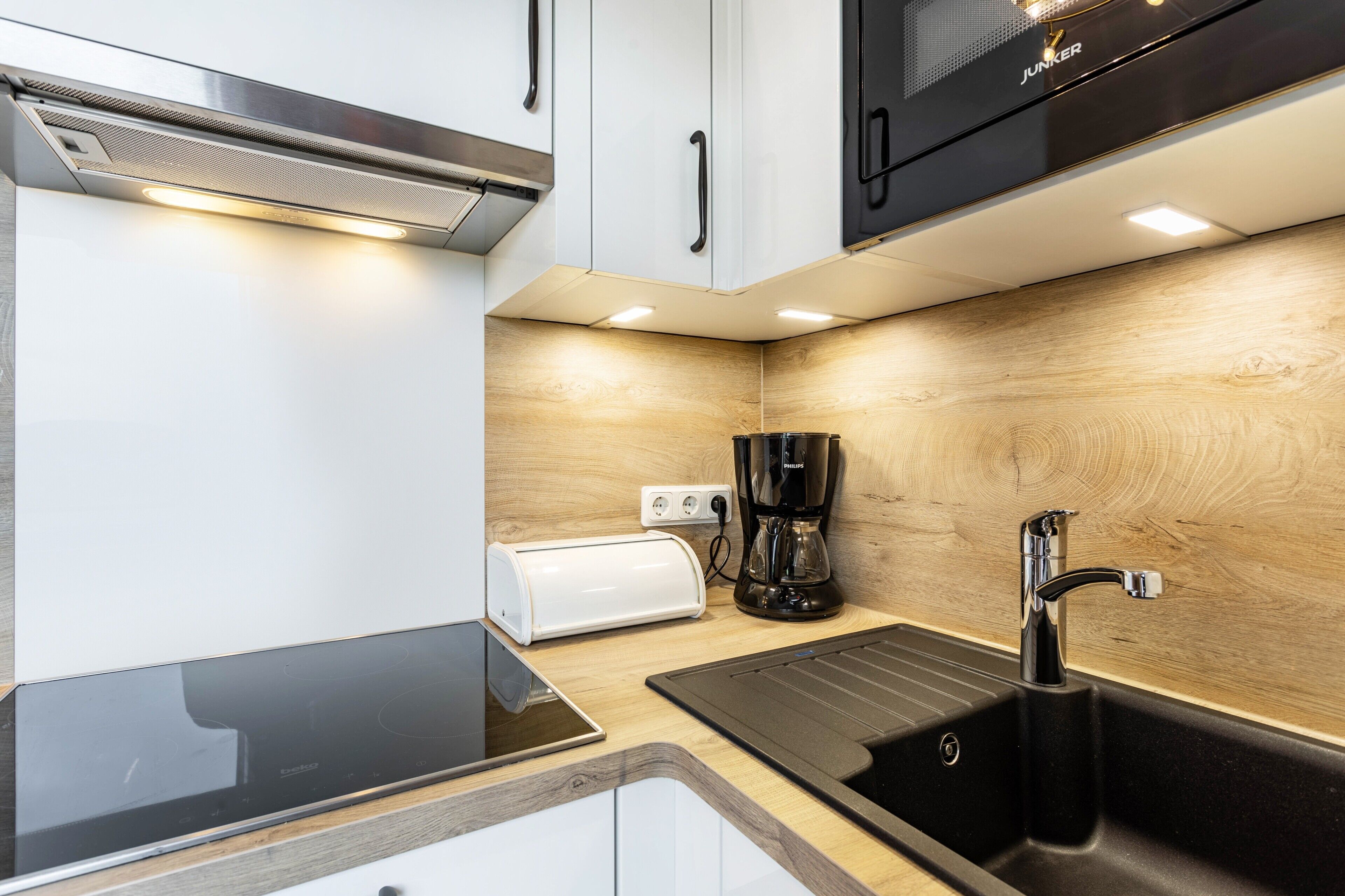 A compact kitchen with a toaster, coffee maker, and a sink.