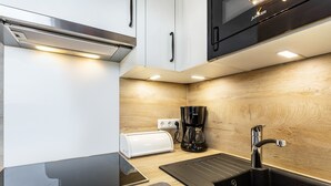 A compact kitchen with a toaster, coffee maker, and a sink.