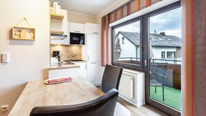 A modern kitchen with white cabinets, a microwave, and a dining area with a table and chairs.