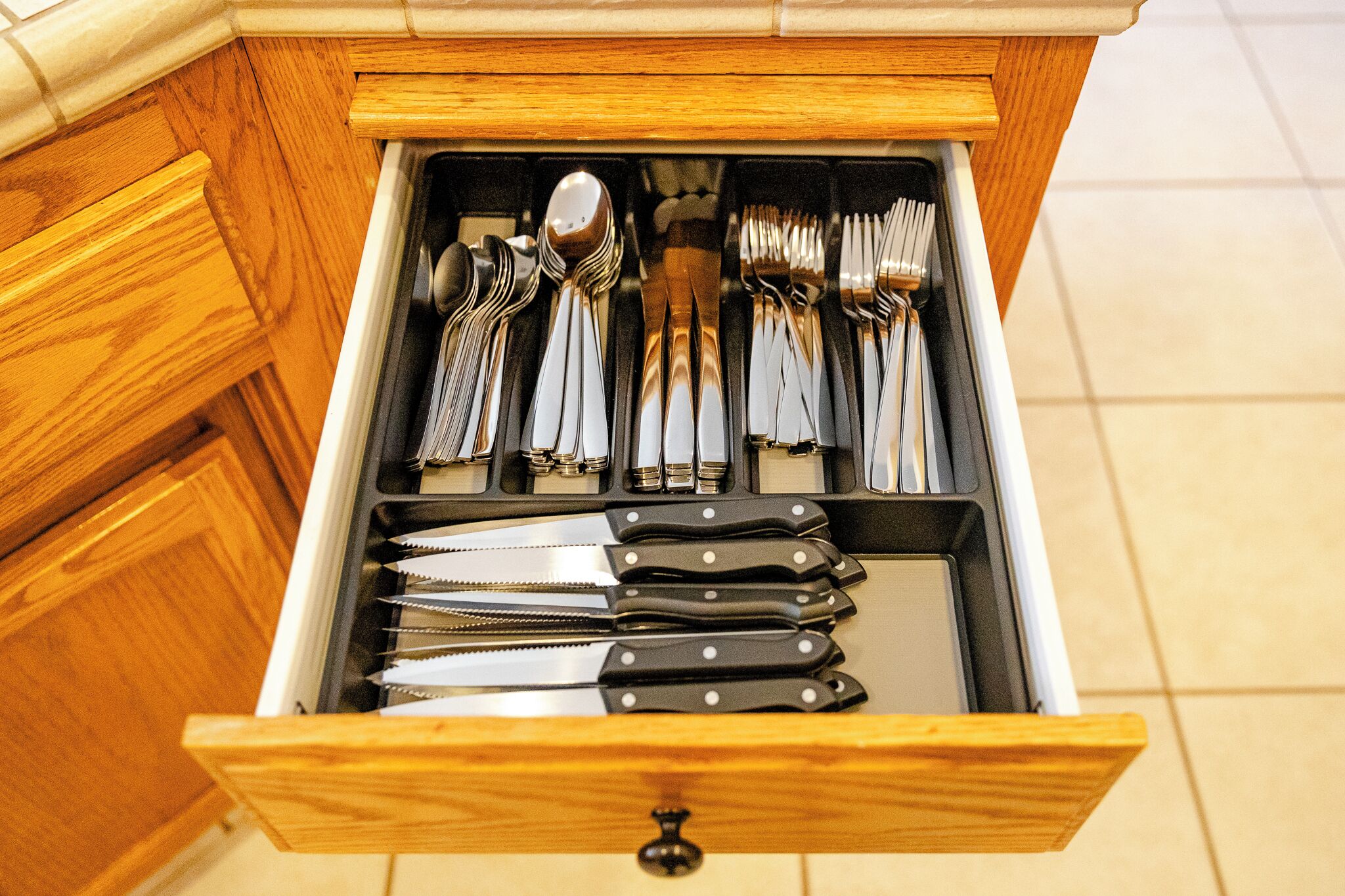 Un tiroir contenant des couverts bien rangés, notamment des fourchettes, des cuillères et des couteaux.