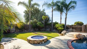 Un patio trasero con una chimenea de piedra, una piscina pequeña y una valla de madera.