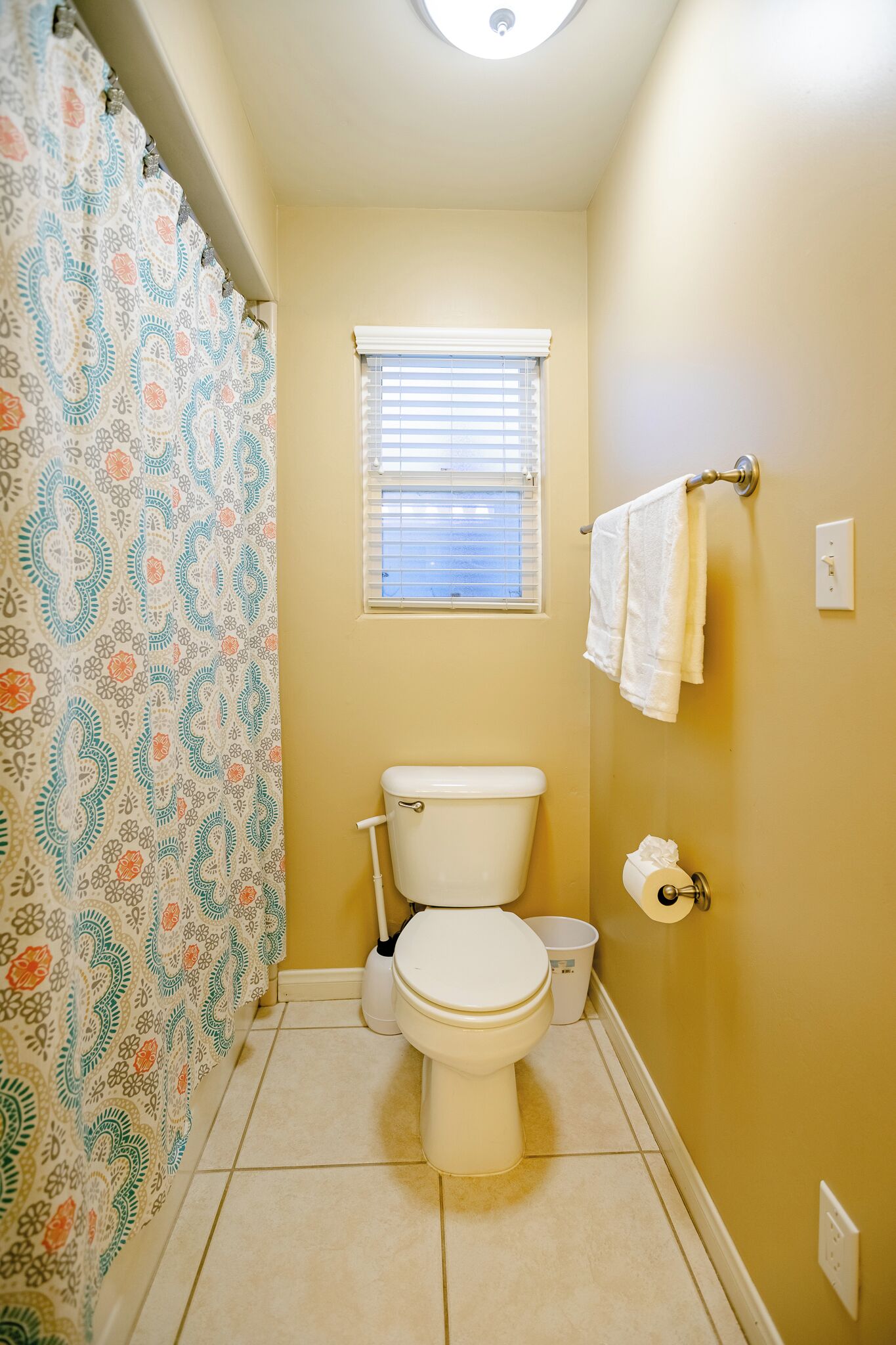 Une petite salle de bain avec des toilettes, une fenêtre et un rideau de douche.