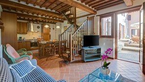 A spacious living area with a wooden staircase, a TV, a sofa, and a dining area. - Home Romeo Private Pool Surrounded by Nature, Borgo a Mozzano, Italy (Borgo a Mozzano)
