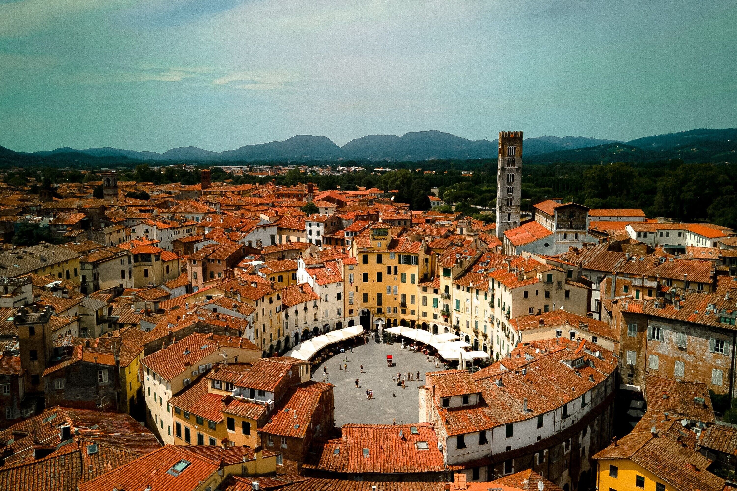 A historic town with a central square surrounded by buildings with red-tiled roofs.
