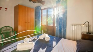 A room with a bed, a green chair, a wooden wardrobe, and a window with curtains. - Home Romeo Private Pool Surrounded by Nature, Borgo a Mozzano, Italy (Borgo a Mozzano)