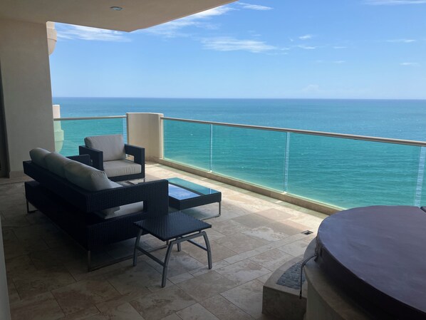 Un balcon avec vue sur l’océan, aménagé avec un canapé, des fauteuils et une petite table.