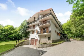 A multi-story building with balconies, a stone wall, and a paved driveway. - Alme Suites near Slopes of Campo Smith, Bardonecchia, Italy (Bardonecchia)