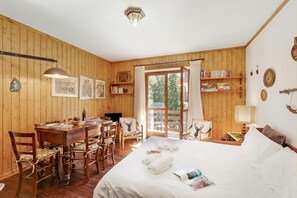A wooden-paneled room with a bed, a desk, chairs, and a bookshelf. - Alme Suites near Slopes of Campo Smith, Bardonecchia, Italy (Bardonecchia)