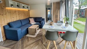 Ein modernes Wohnzimmer mit einem blauen Sofa, einem Glastisch und einem Holzboden mit Fischgrätmuster.