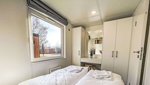 Ein Zimmer mit zwei Betten, einem Fenster, einem Spiegel und einem Kleiderschrank.