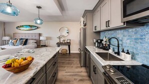 Een moderne keuken met marmeren aanrechtbladen, roestvrijstalen apparatuur en blauwe spatborden.