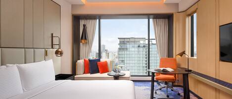 Una habitación de hotel con una cama grande, un sofá, un escritorio y un televisor.
