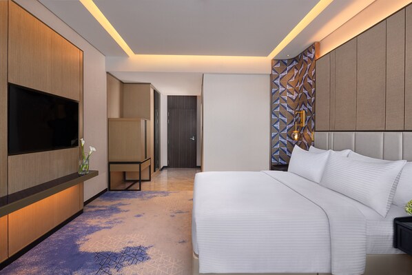 Habitación de hotel moderna con una cama grande, un televisor de pantalla plana, un escritorio y una pared con diseño.