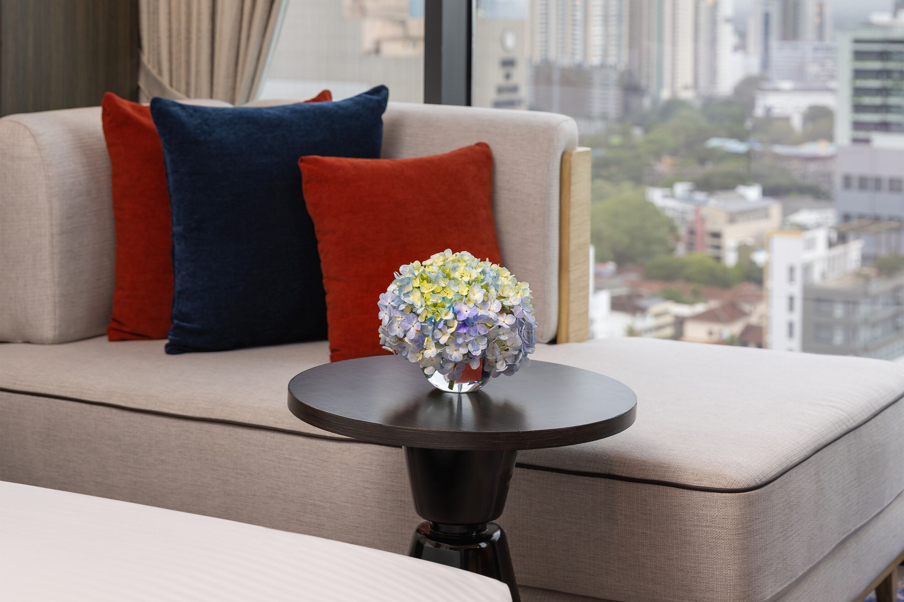 A modern living room with a sofa, a round table, and a vase of flowers.