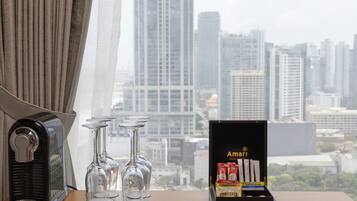 A table with a coffee maker, three wine glasses, and a box of Amari and Basillier chocolates.