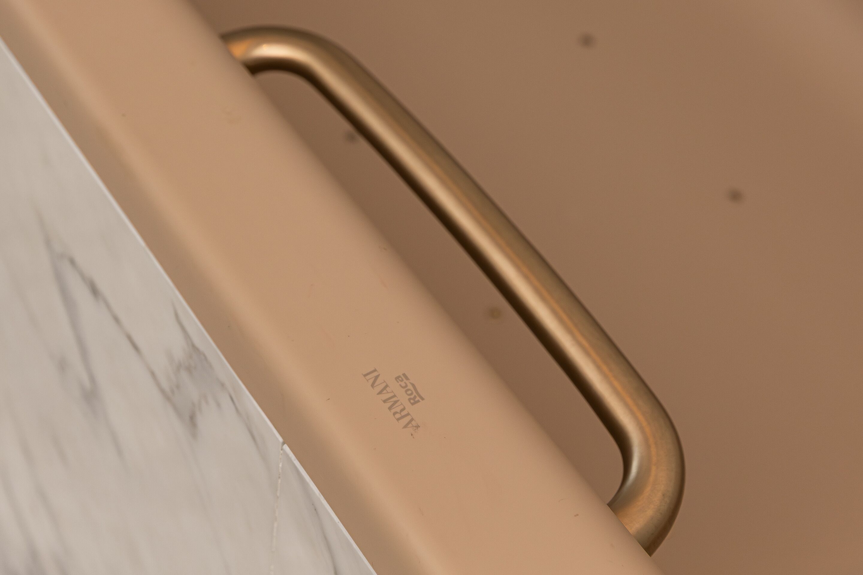 Une poignée métallique sur un objet de couleur beige, qui pourrait être un meuble ou un appareil.