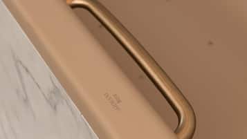 Une poignée métallique sur un objet de couleur beige, qui pourrait être un meuble ou un appareil.