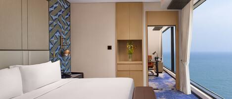 Habitación de hotel moderna con una cama grande, un escritorio y vista al océano.