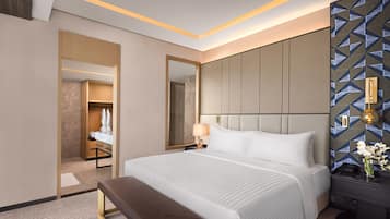 Una habitación de hotel moderna con una cama grande, un banco, una mesita de noche y un espejo.