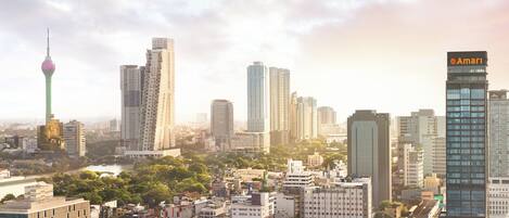 A cityscape with modern high-rise buildings, a prominent tower, and a mix of greenery.