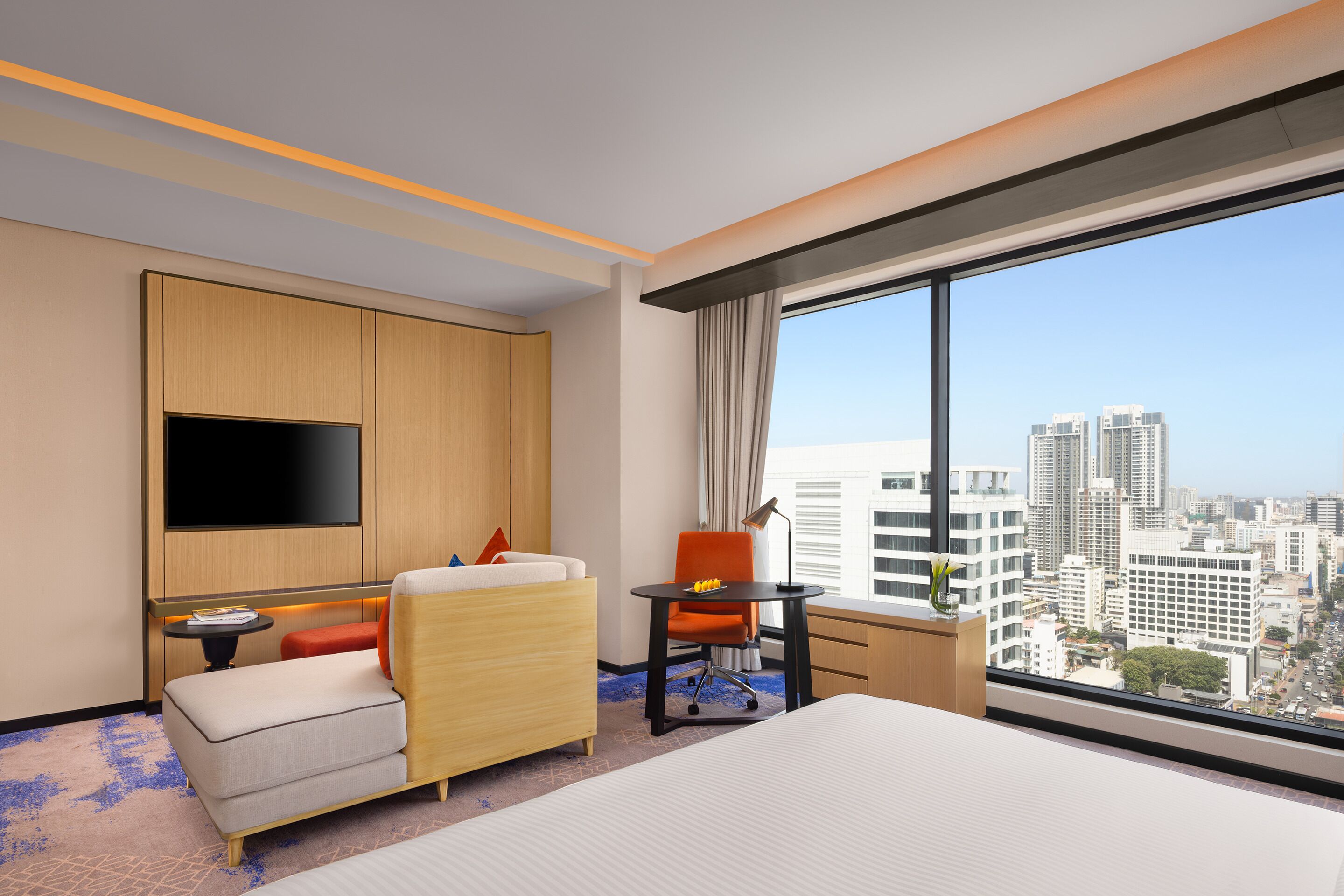 A hotel room with a bed, a TV, a desk, and a chair.