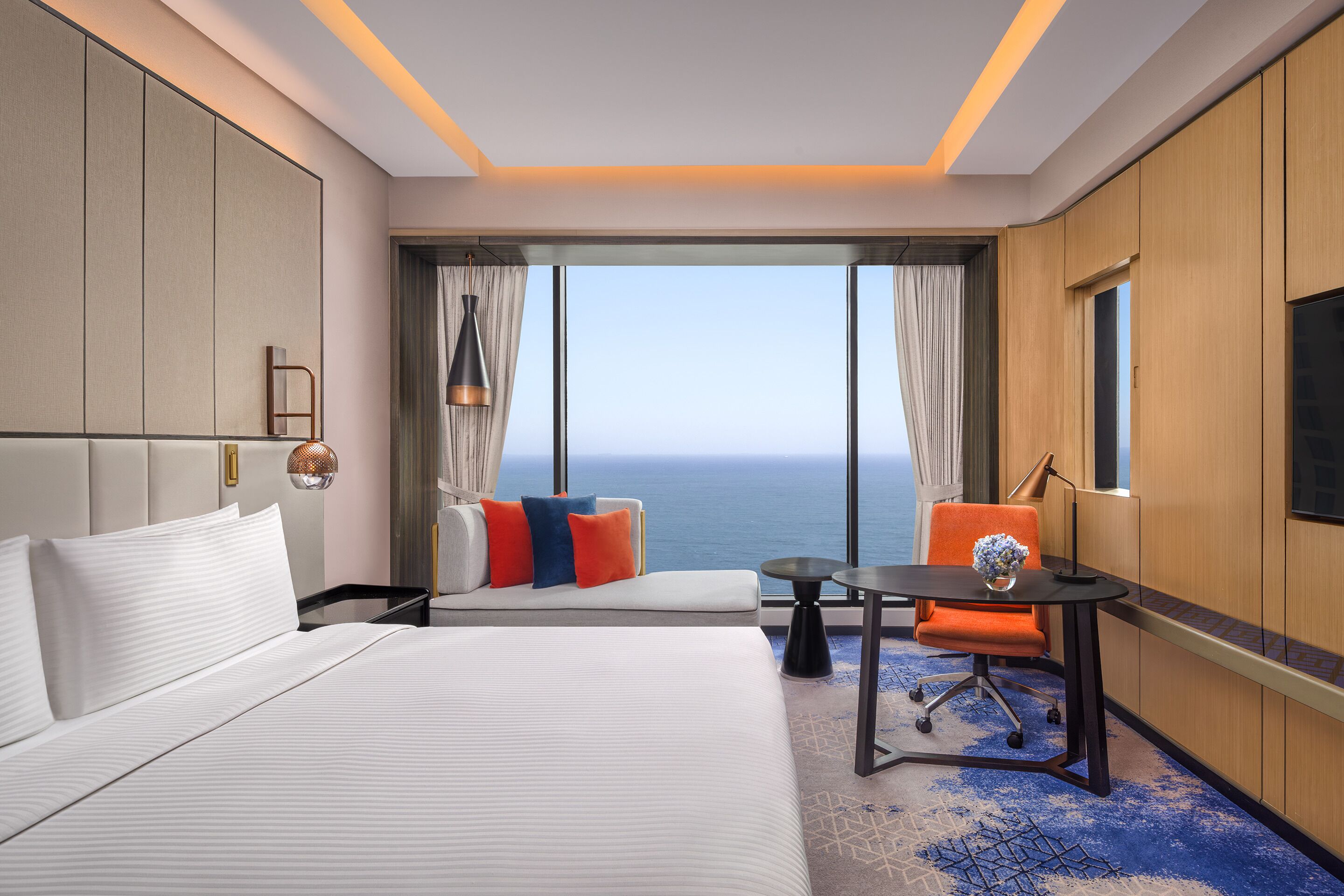 Une chambre d’hôtel avec un grand lit, un bureau, une chaise et une vue sur l’océan.