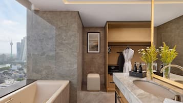 A modern bathroom with a bathtub, a sink with a large mirror, and a view of the cityscape.