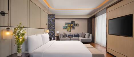 Une chambre à coucher moderne avec un grand lit, un canapé, une télévision et des œuvres d’art accrochées au mur.