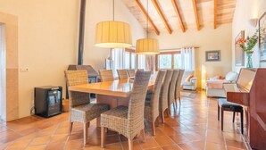 A dining area with a wooden table and wicker chairs, a fireplace, and a sofa in the background. - Can Raull in Cales de Mallorca (Manacor)