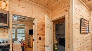 Ein Holzblockhaus-Interieur mit Küchenzeile, Esstisch und einem Bett.