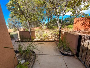A paved patio area with a concrete pathway, surrounded by a low wall and various plants. - Fairway Foothills - 3335 (Moab)
