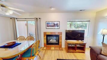 Una sala de estar con chimenea, televisor, mesa de comedor con sillas y sofá.
