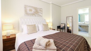 A neatly made bed with a brown and white checkered bedspread, a white headboard, and two bedside lamps. - Privilegio de Marbella near Puerto Banus (Marbella)