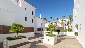 A courtyard with white buildings, planters with greenery, and a bench. - Privilegio de Marbella near Puerto Banus (Marbella)