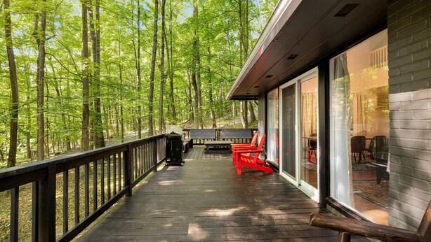 A wooden deck with a railing, a barbecue grill, and outdoor seating. - Cozy cabin w/hot tub & wraparound deck (Berkeley Springs)