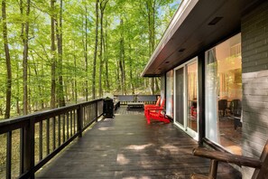 A wooden deck with a railing, a barbecue grill, and outdoor seating. - Cozy cabin w/hot tub & wraparound deck (Berkeley Springs)