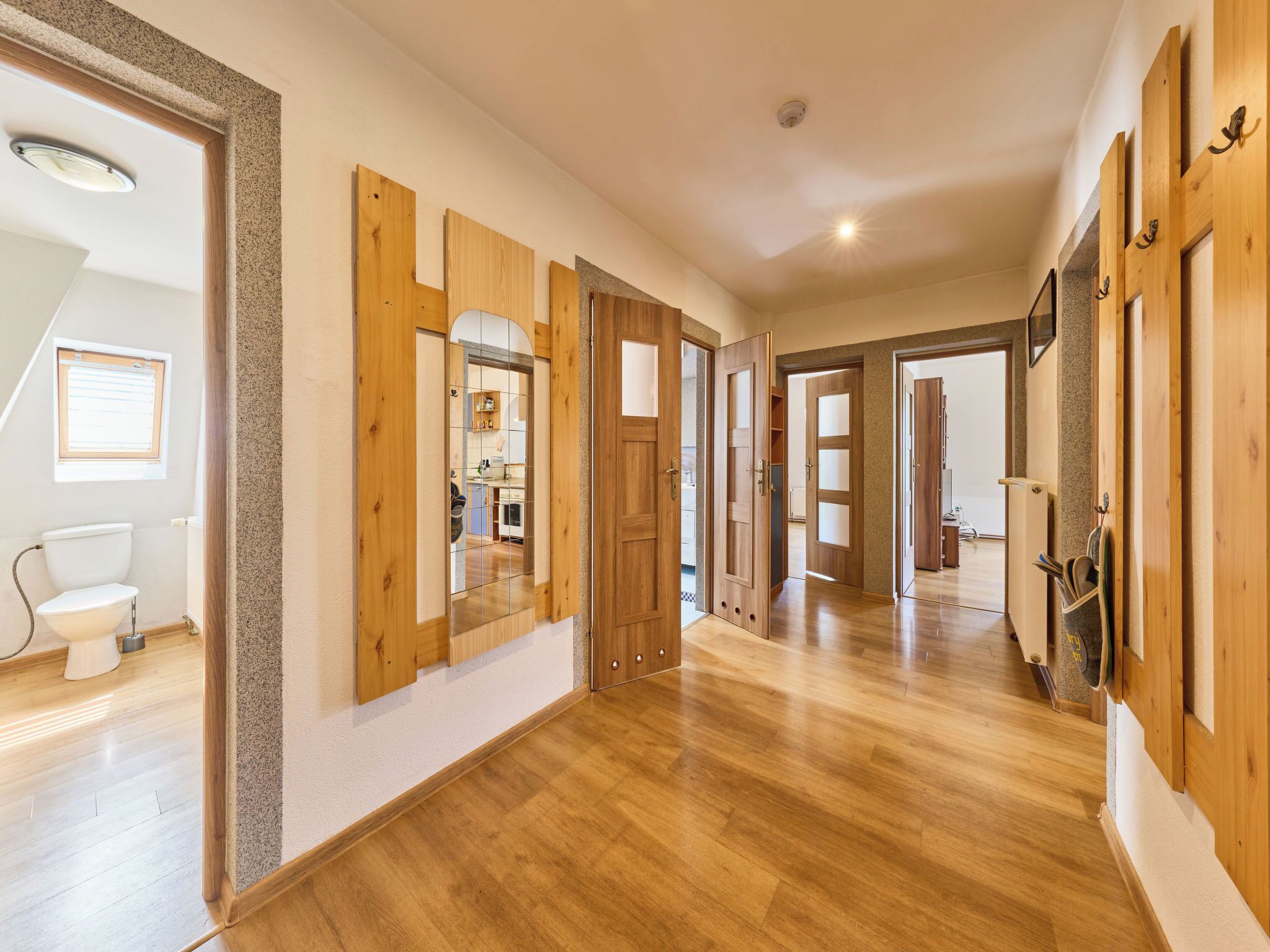 Un pasillo amplio con puertas de madera y vista a una zona de cocina.